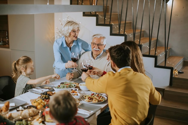 Famille heureuse en train de dîner avec du vin rouge à la maison