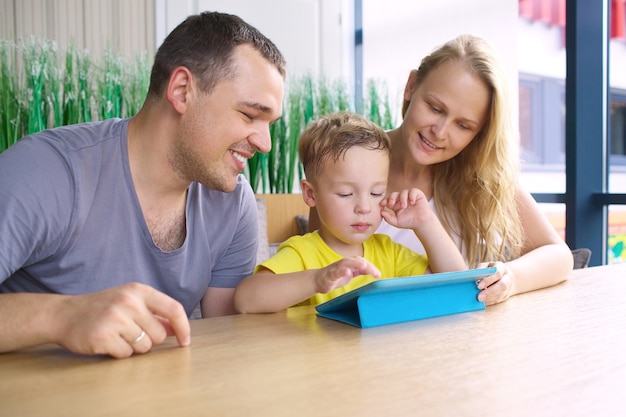 Famille heureuse de trois avec tablette dans le café