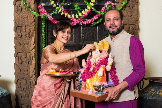 Famille indienne célébrant Ganesh Chaturthi en faisant Ganpati Puja ou poojan