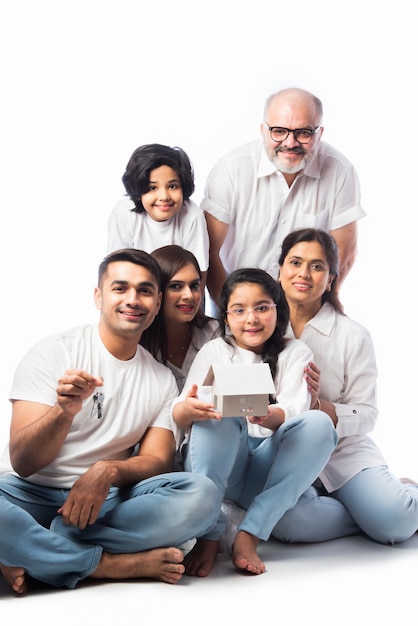 Famille indienne et concept immobilier - Famille asiatique multigénérationnelle tenant un modèle de maison en papier avec des clés sur fond blanc