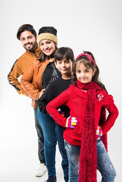 Famille indienne dans des vêtements chauds debout sur fond blanc. Prêt pour l'hiver