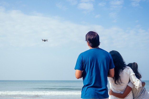 Une famille indienne heureuse exploite le drone par télécommande sur la plage de Goa