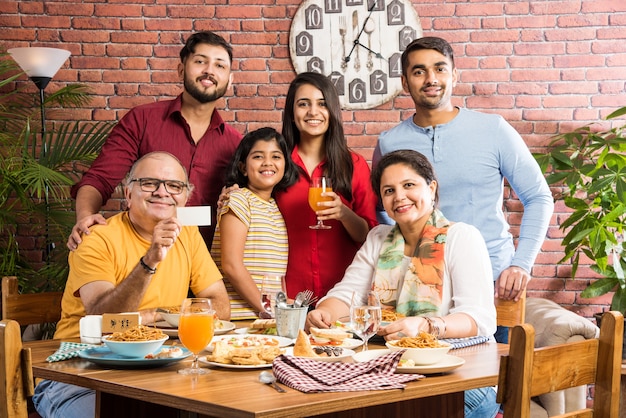 Famille indienne mangeant de la nourriture à la table à manger à la maison ou au restaurant en train de manger ensemble