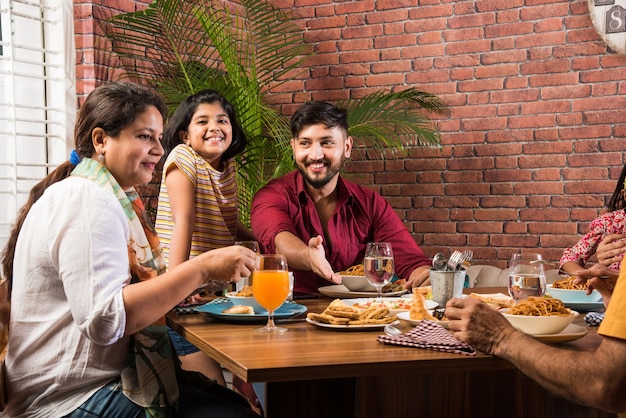 Famille indienne mangeant de la nourriture à la table à manger à la maison ou au restaurant en train de manger ensemble