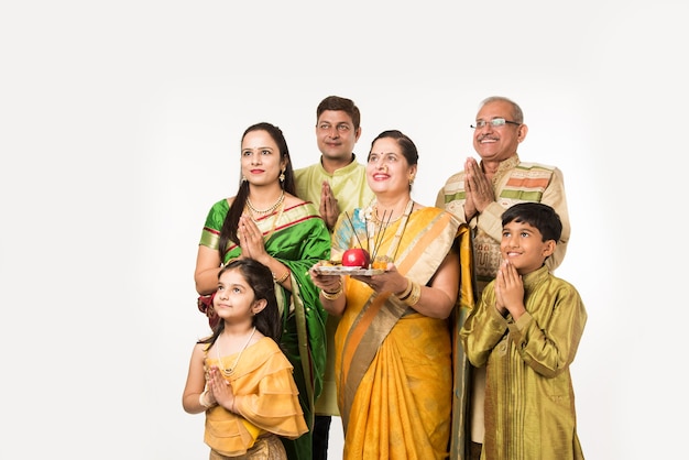 Famille Intelligente Indienne Asiatique Accueillant Lord Ganesha Idol Lors Du Festival De Ganesh Avec Pooja Thali Et Des Bonbons. Debout Isolé Sur Fond Blanc