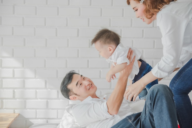 Famille japonaise asiatique père mère fils portant chemise blanche portant enfant sur chambre à coucher dans la salle blanche.