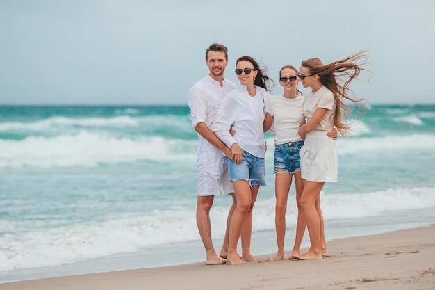 Famille d'un jeune parent et de deux enfants souriants et profitant du temps ensemble pendant les vacances à la plage