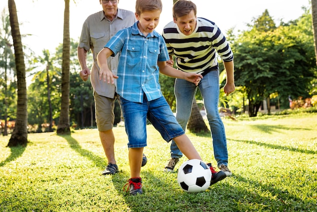 Famille jouant au football dans le jardin