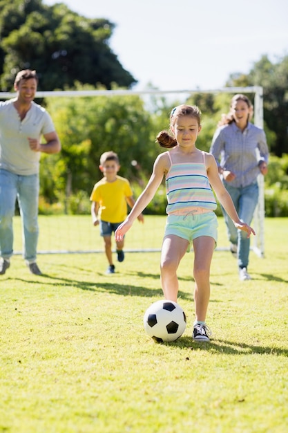 Famille jouant au football ensemble dans le parc