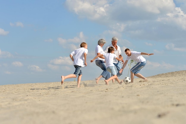 Famille jouant au football sur une plage