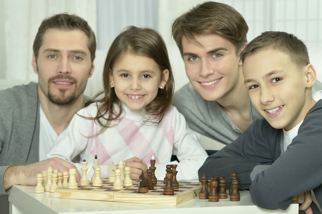 Famille jouant aux échecs sur une table à la maison