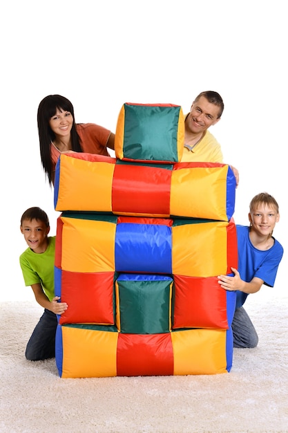 Famille jouant avec des coussins colorés sur fond blanc