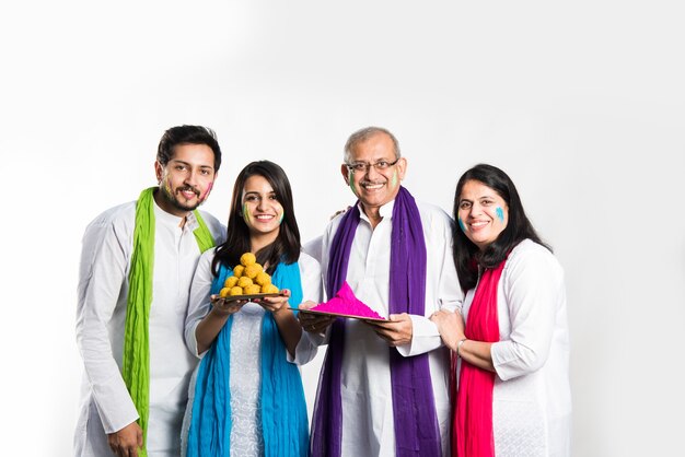 Famille jouant holi, tenant une assiette pleine de doux laddu et de couleurs. isolé sur fond blanc