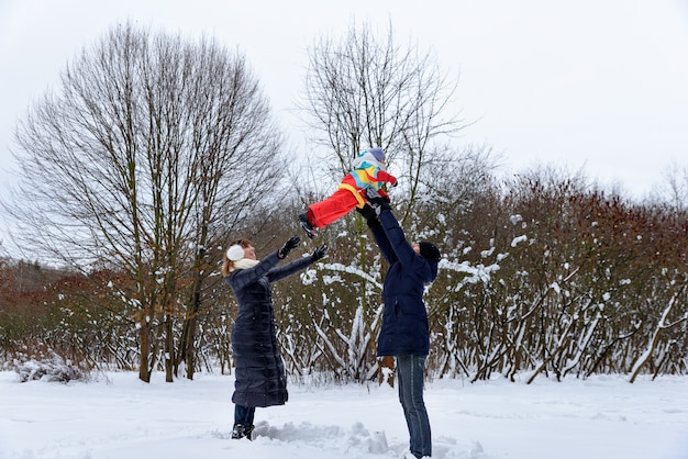 Famille jouant avec leur enfant dans la neige