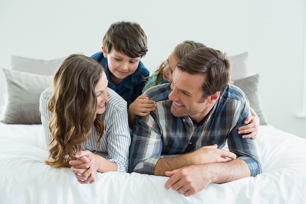 Famille jouant sur le lit dans la chambre à la maison