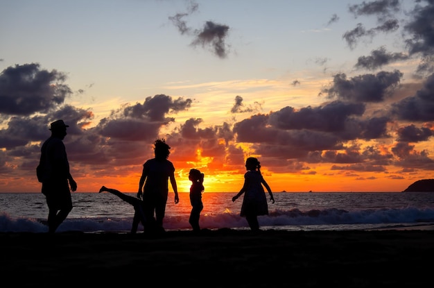 Famille jouant sur la plage au beau coucher de soleil avec coucher de soleil