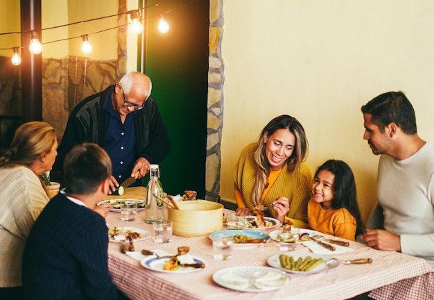 Une famille latine heureuse cuisine ensemble pendant l'heure du dîner à la maison. Concentrez-vous sur le visage du grand-père