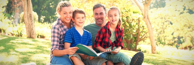 Famille lisant un livre dans le parc par une journée ensoleillée