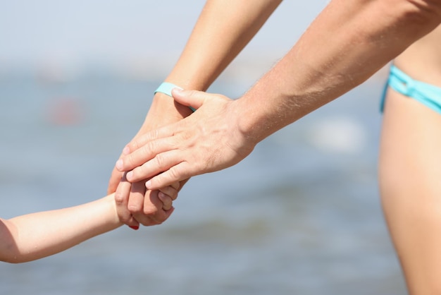 Famille main dans la main mère père et enfant marchant sur le littoral