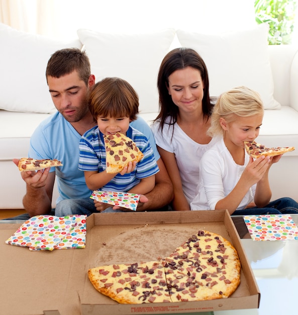 Famille, manger des pizzas dans le salon