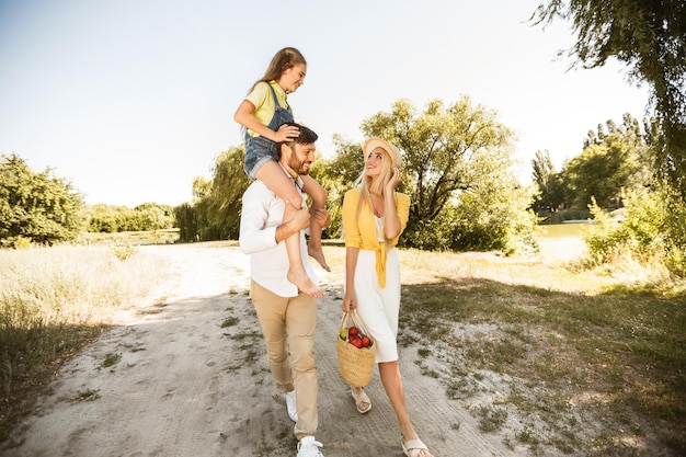 Famille marchant dans la nature fille assise sur les épaules du père