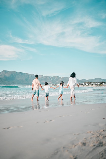 La famille marche sur la plage main tenant et vue arrière sur l'océan et les liens pendant les vacances liberté et voyage Parents jeunes enfants et solidarité en vacances tropicales au Mexique amour et soins en plein air