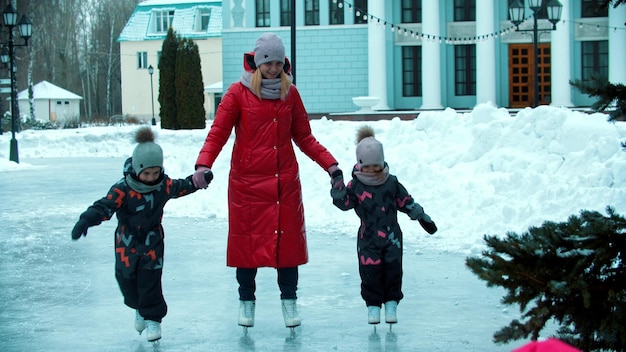 Une famille de mère et deux enfants patinant sur la glace femme tenant leurs mains