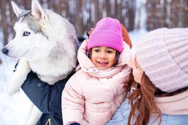 Photo famille métisse en trio passant les vacances du nouvel an dans un parc avec leur chien husky