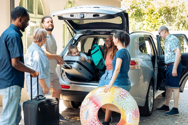 Famille mixte et amis partant en vacances, préparant un véhicule avec des sacs et des bagages pour partir en vacances d'été. Personnes multiethniques voyageant à l'aventure avec des bagages en automobile.