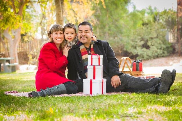Une famille mixte se réjouit ensemble des cadeaux de Noël dans le parc