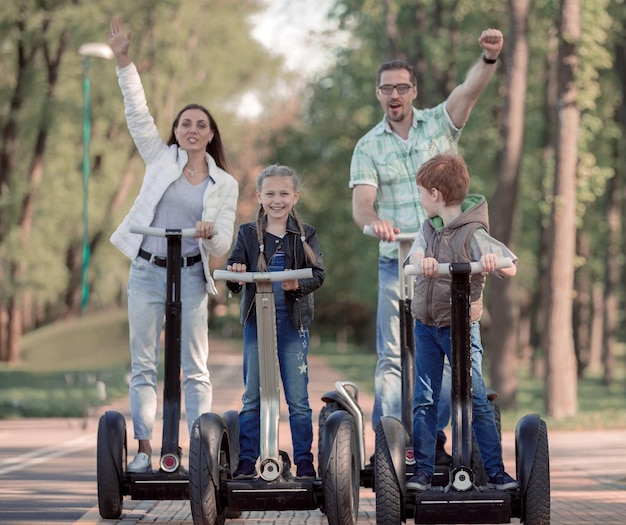 Famille moderne chevauchant un mini hoverboard électrique dans le parc