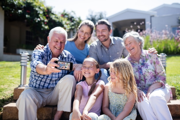 Photo famille multi-génération prenant un selfie dans le jardin