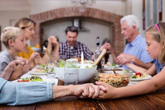 Famille multi-génération priant avant de prendre son repas