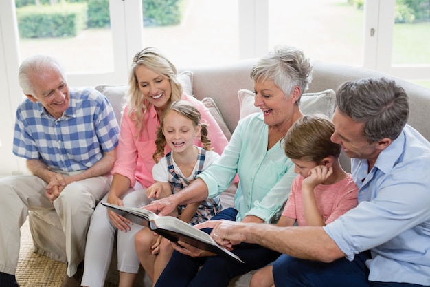 Famille multi-générationnelle regardant sa photo d'album dans le salon