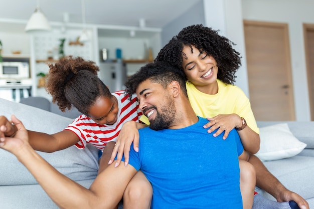 Famille multiethnique joyeuse positive femme mari enfant assis ensemble sur le canapé à la maison Gros plan sur la petite fille et la belle mère Heureuse famille multiraciale concep