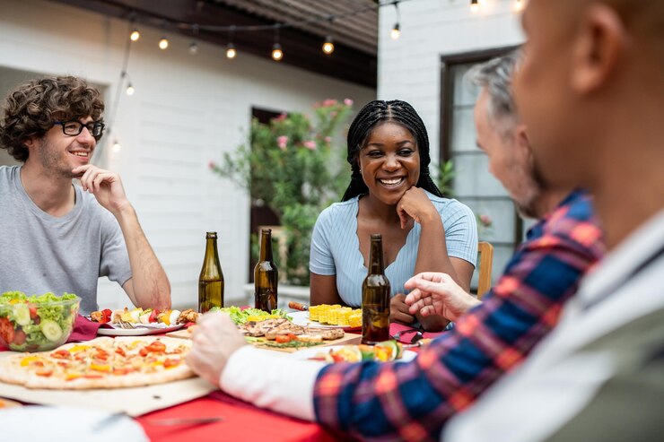 Photo une famille multiethnique s'amusant, faisant la fête à l'extérieur dans le jardin, un groupe diversifié et attrayant de gens dînant, mangeant de la nourriture, célébrant la réunion du week-end, rassemblés à la table à manger.