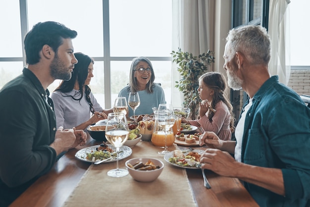 Famille multigénérationnelle souriante communiquant tout en dînant ensemble