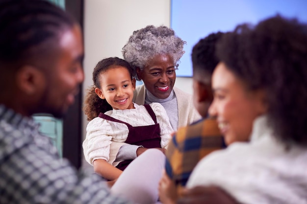 Famille multigénérationnelle souriante se relaxant dans le salon à la maison ensemble