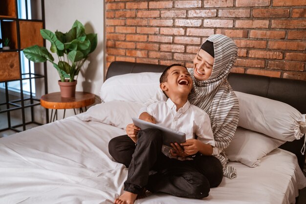 Famille musulmane à l'aide de tablette sur le lit