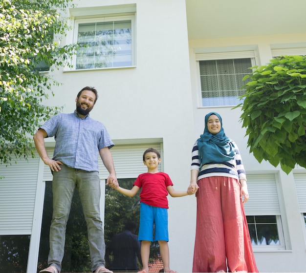 Famille musulmane devant une belle maison moderne