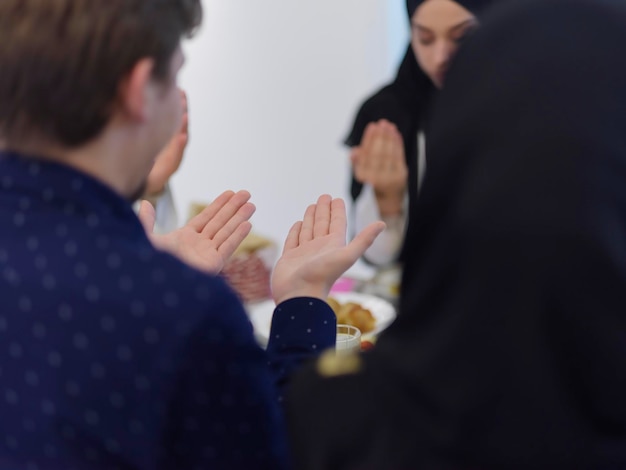 Famille musulmane faisant de l'iftar dua pour rompre le jeûne pendant le Ramadan. Les Arabes se tiennent la main pour prier et remercier Allah avant le dîner traditionnel