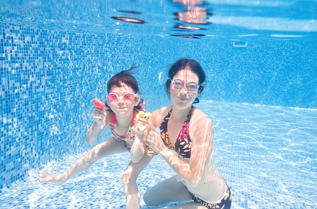 Famille nage dans la piscine sous l'eau, heureuse mère et enfant actifs s'amusent sous l'eau, fitness et sport avec enfant en vacances d'été sur la station