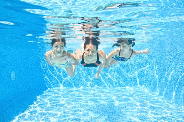 Famille nage sous l'eau dans la piscine mère active heureuse et les enfants s'amusent sous l'eau