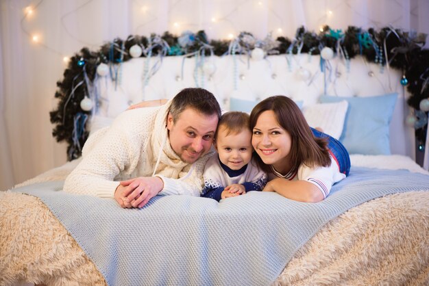 Famille de Noël. Bonne maman, papa et petit fils allongés sur le lit. Enjoyng calins d'amour, les gens de vacances.