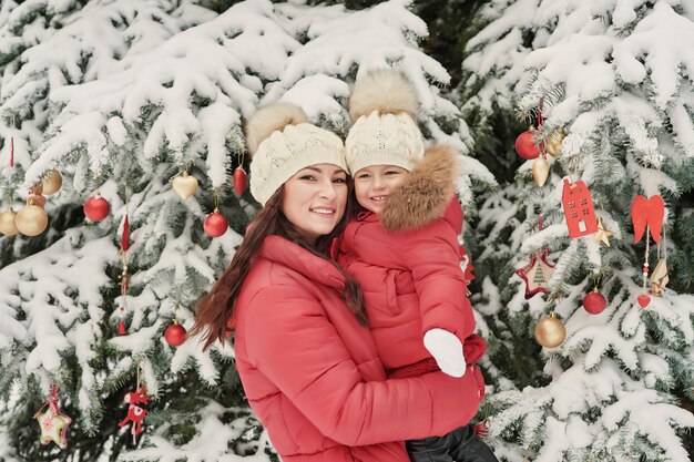 Famille de Noël à winter park. Heureuse mère de famille et fille enfant s'amuser, jouer à la promenade d'hiver à l'extérieur. Plaisir en famille en plein air pendant les vacances de Noël.Vêtements d'hiver pour bébé et enfant en bas âge.