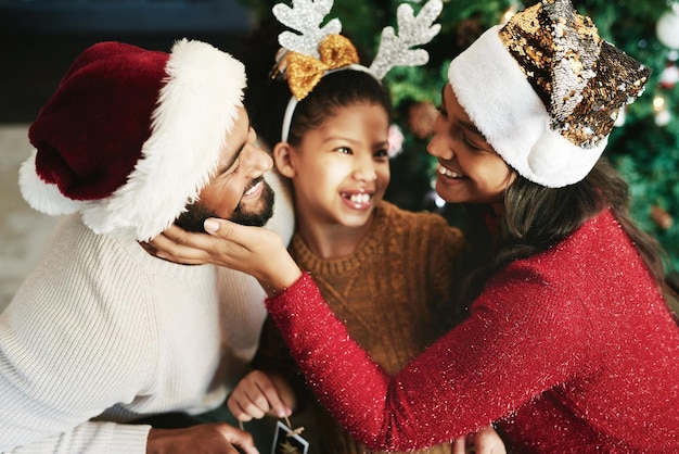 Photo famille noire heureuse et célébrer les vacances de noël ensemble pour le soutien et les soins de l'amour bonheur parents et enfant sourient pour des vacances festives à la maison avec un arbre de noël dans le salon