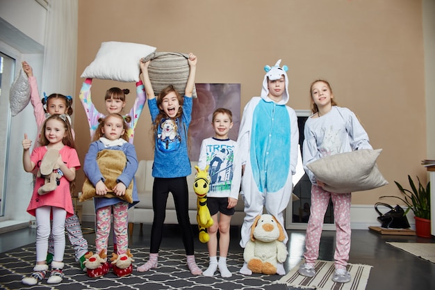 Famille nombreuse, les enfants s'amusent et jouent le matin à la maison. Garçons et filles en pyjama de nuit