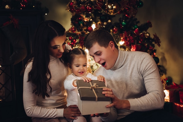 Famille ouvrant le cadeau de Noël ensemble. chambre décorée pour Noël.