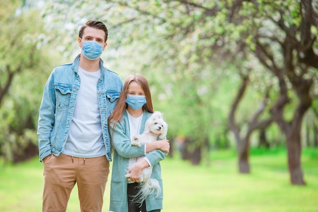 Famille de papa et enfant avec chien portant un masque médical de protection pour prévenir le virus à l'extérieur dans le parc