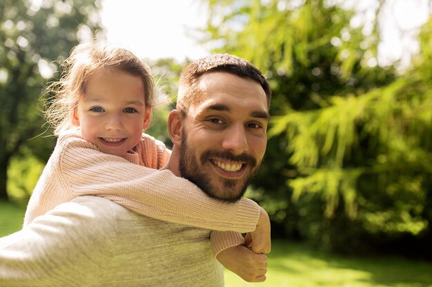 Photo famille, parentalité, paternité et concept de personnes - père heureux et petite fille s'amusant dans le parc d'été